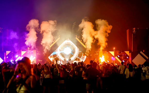 Crowd enjoying a vibrant night concert at Emirates Dubai 7s with colorful lights and smoke effects.