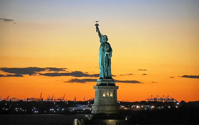 Statue of Liberty at sunset during Ellis Island sightseeing cruise.