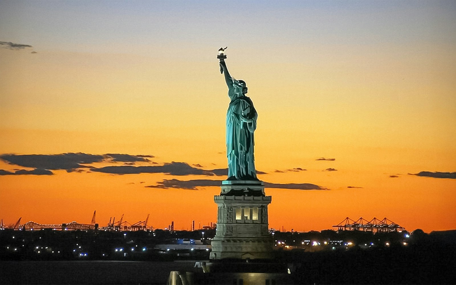 Statue of Liberty and Ellis Island cruise boat with tourists in New York Harbor.