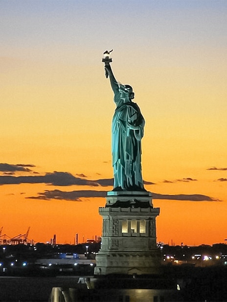 Statue of Liberty at sunset during Ellis Island sightseeing cruise.