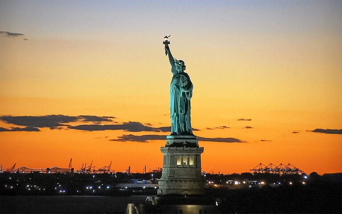 Statue of Liberty at sunset during Ellis Island sightseeing cruise.