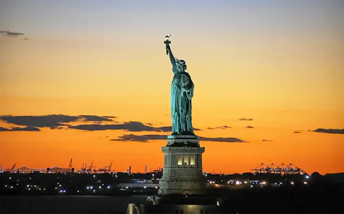 Statue of Liberty at sunset during Ellis Island sightseeing cruise.