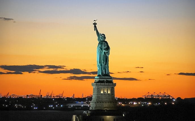 Statue of Liberty at sunset during Ellis Island sightseeing cruise.