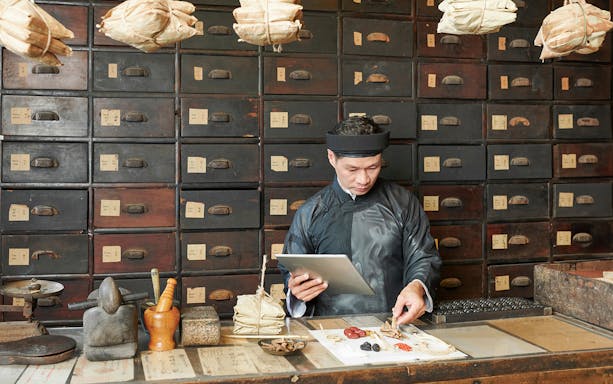 Herbalist preparing traditional medicine in Kuala Lumpur shop during street food tour.