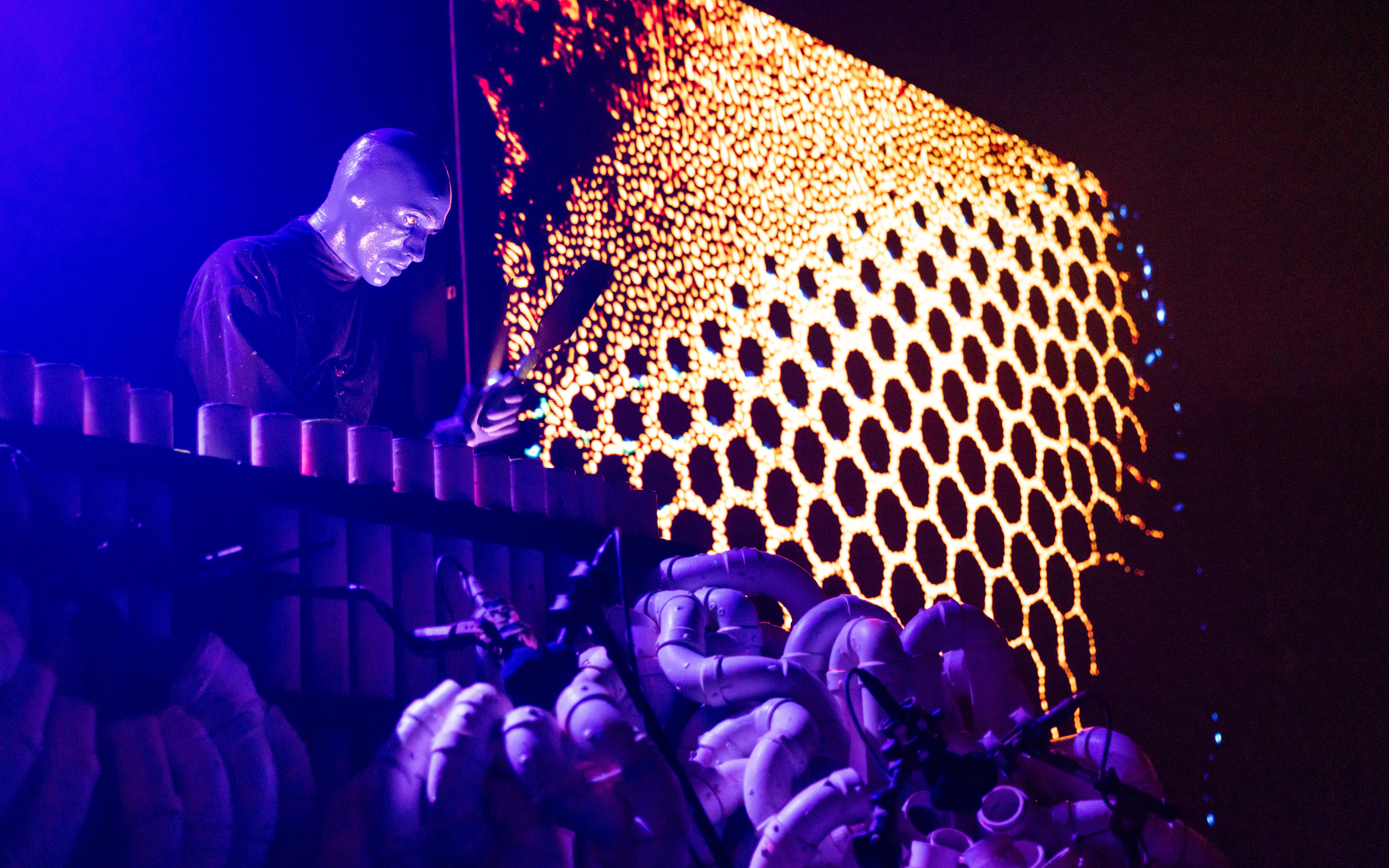 Blue Man Group performing with pipes on stage, Orlando.