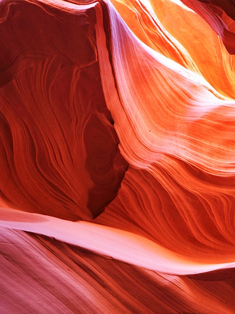 Antelope Canyon's swirling red rock formations illuminated by sunlight.