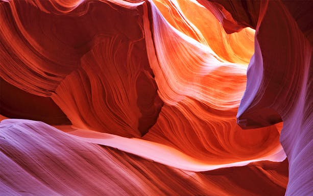 Antelope Canyon's swirling red rock formations illuminated by sunlight.
