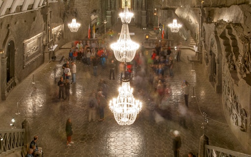 Wieliczka Salt Mine chamber with chandeliers and visitors exploring the historic site.