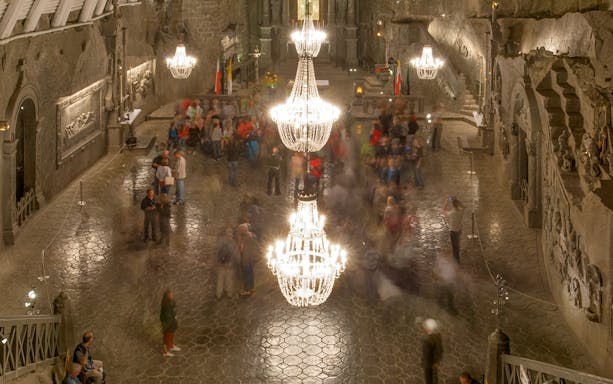 Wieliczka Salt Mine chamber with chandeliers and visitors exploring the historic site.