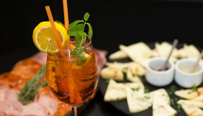 Traditional Italian aperitif with prosciutto, mortadella, cheese, and Aperol Spritz in Italy.