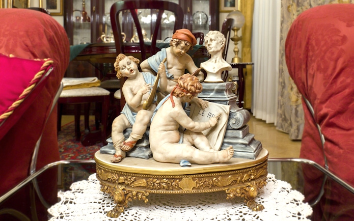 Capodimonte porcelain figurines depicting cherubs with musical instruments and a bust in an ornate room.