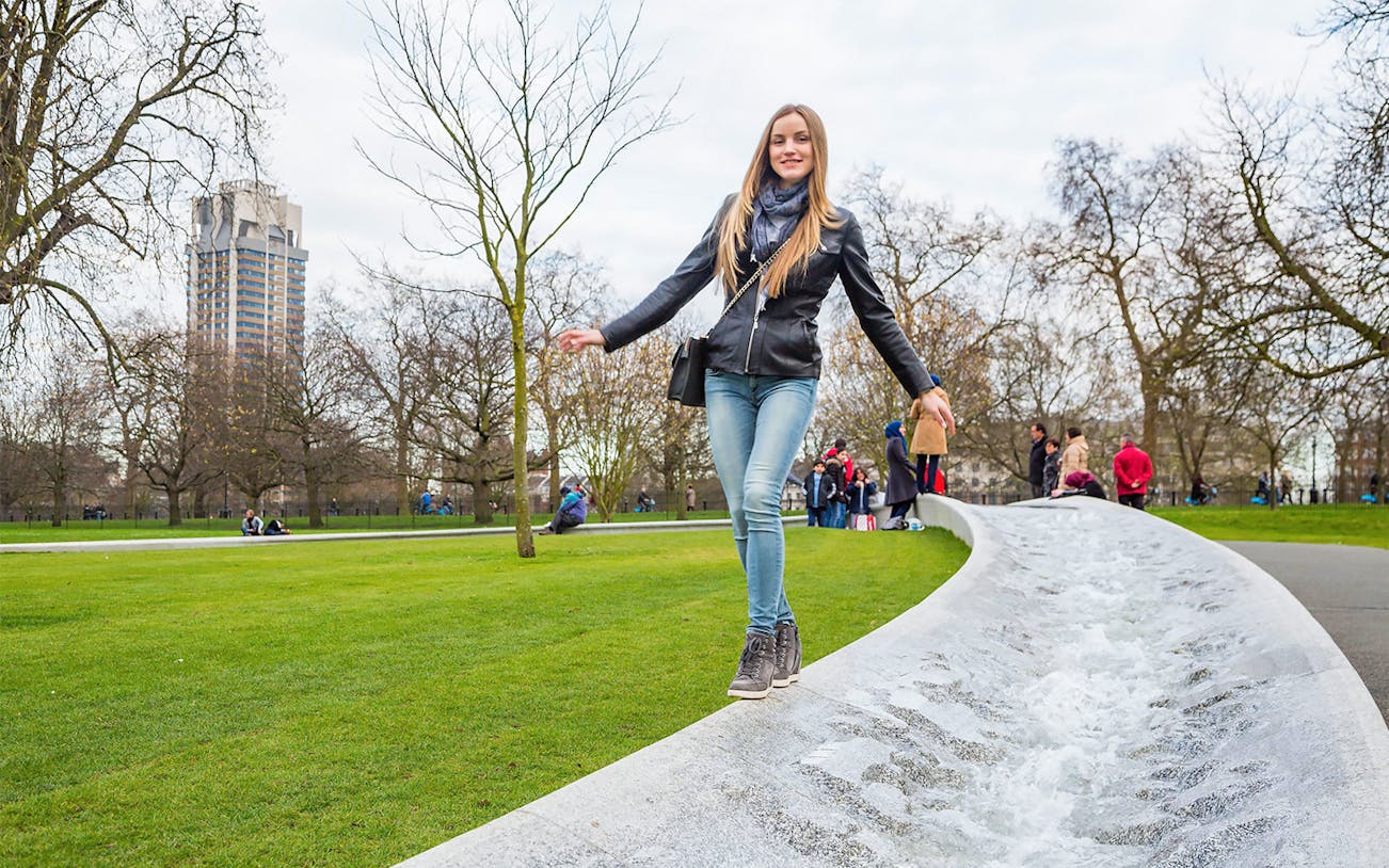 Woman walking along the Diana Memorial Fountain in Hyde Park, London.