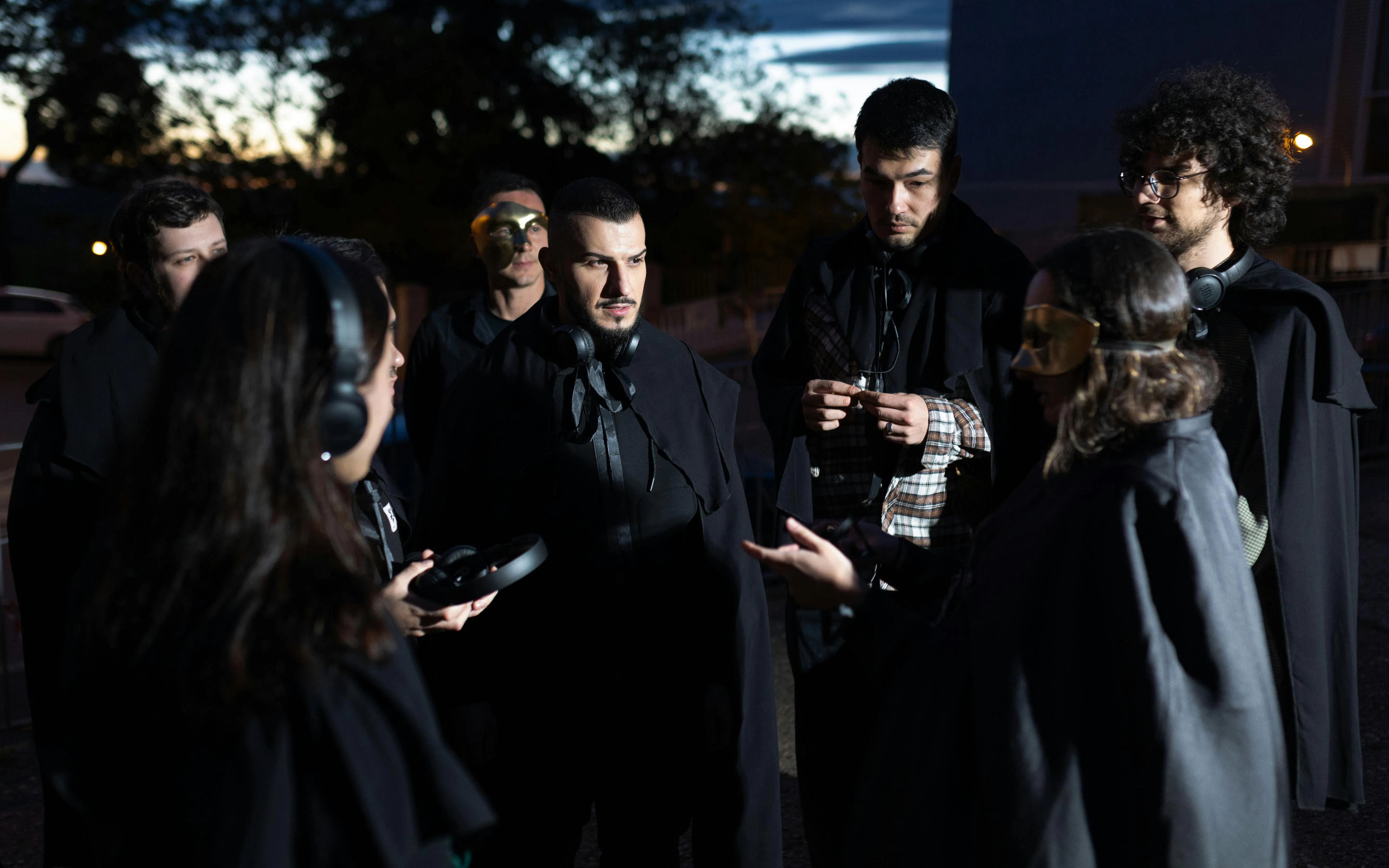 Tourists in cloaks and masks during a theatrical tour in Madrid at dusk.