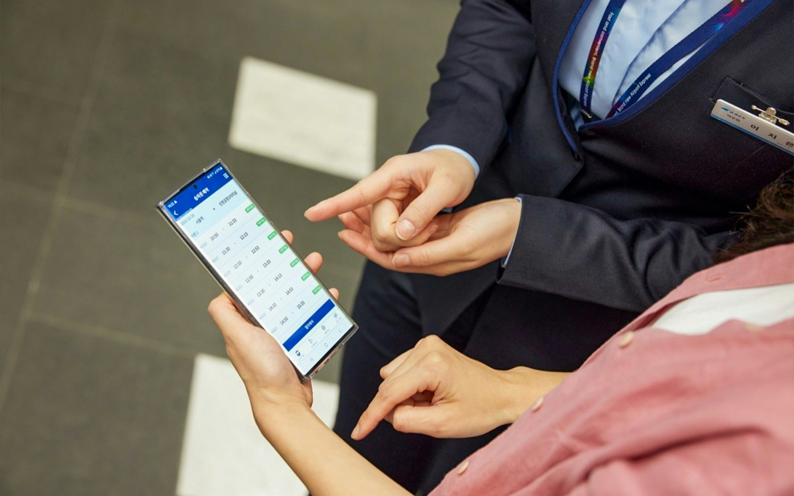 People checking train schedule on a smartphone for AREX Express to Lotte World.