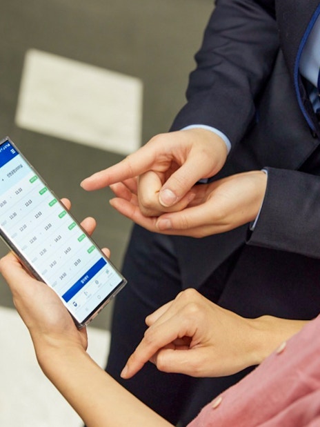 People checking train schedule on a smartphone for AREX Express to Lotte World.
