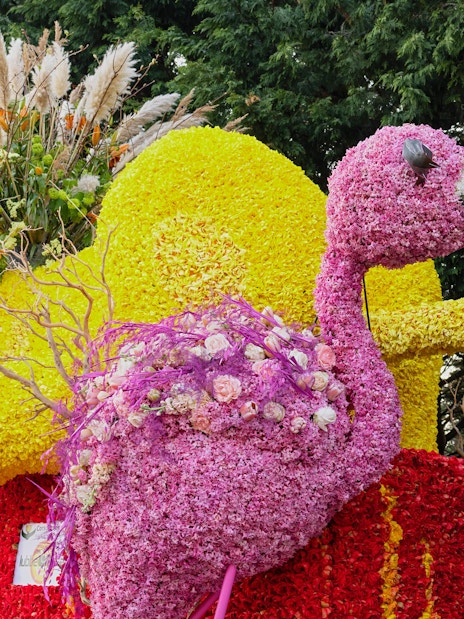 Floral sculpture of a flamingo made from pink tulips and hyacinths, surrounded by colorful blooms.