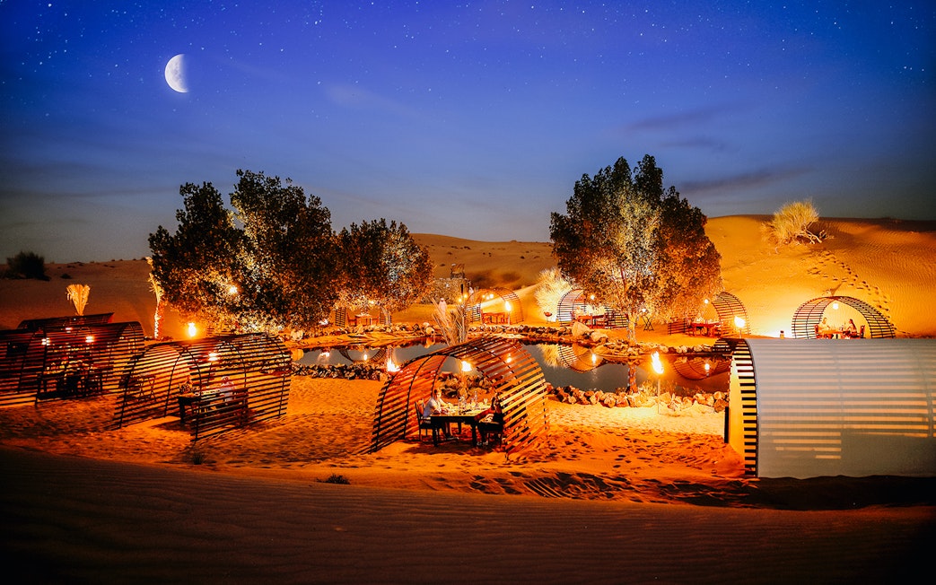 Private cabanas under a starry sky in a desert oasis, Dubai.