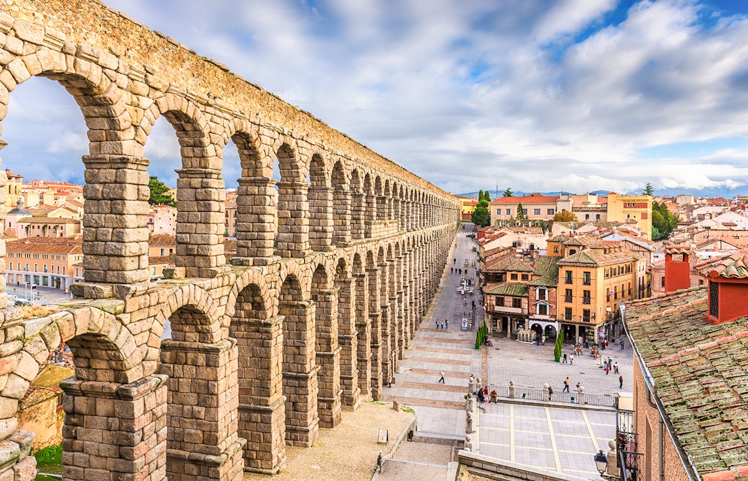 Ancient Roman aqueduct in Segovia, Spain, overlooking city streets and historic buildings.