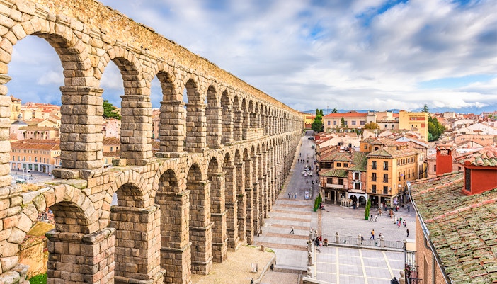 Ancient Roman aqueduct in Segovia, Spain, overlooking city streets and historic buildings.