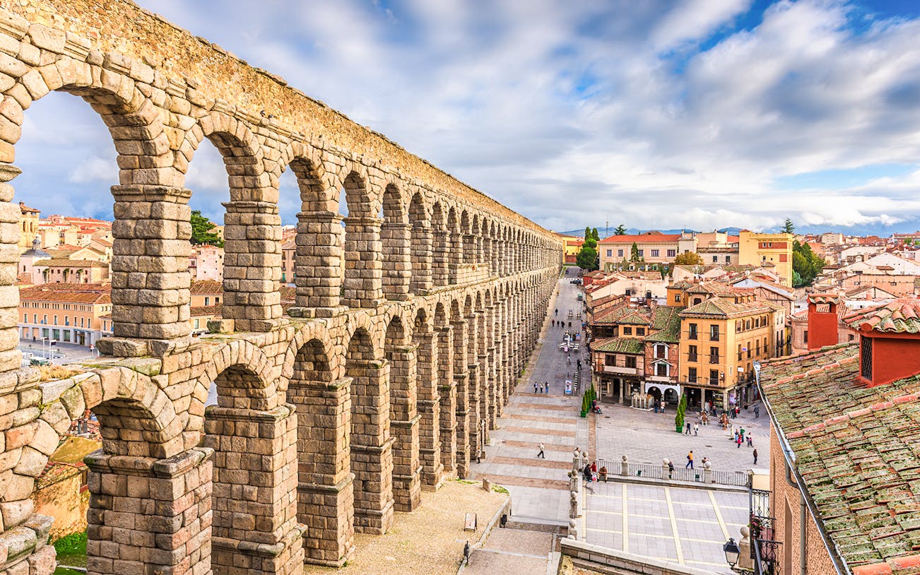 Ancient Roman aqueduct in Segovia, Spain, overlooking city streets and historic buildings.