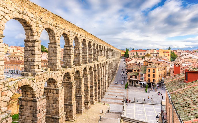 Ancient Roman aqueduct in Segovia, Spain, overlooking city streets and historic buildings.