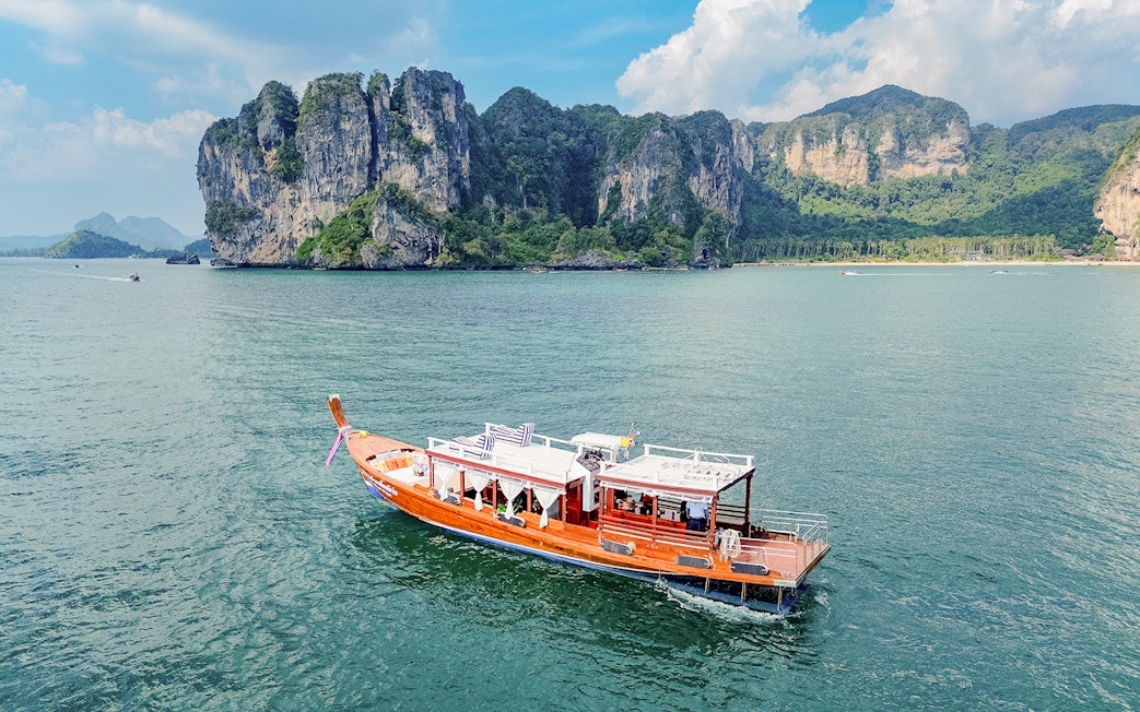 Long tail boat on the water near limestone cliffs, Ko Hong, Thailand.