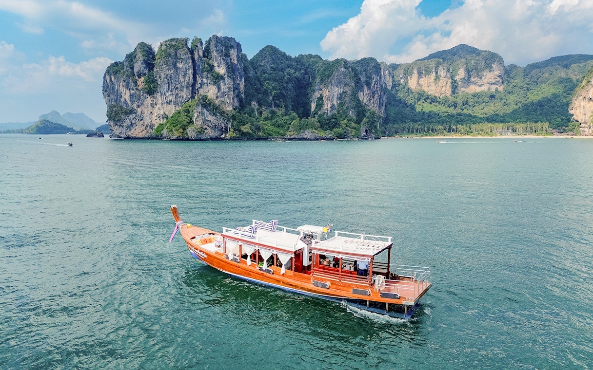 Long tail boat on the water near limestone cliffs, Ko Hong, Thailand.
