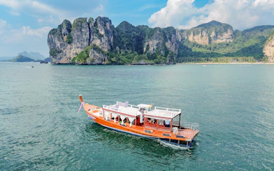 Long tail boat on the water near limestone cliffs, Ko Hong, Thailand.