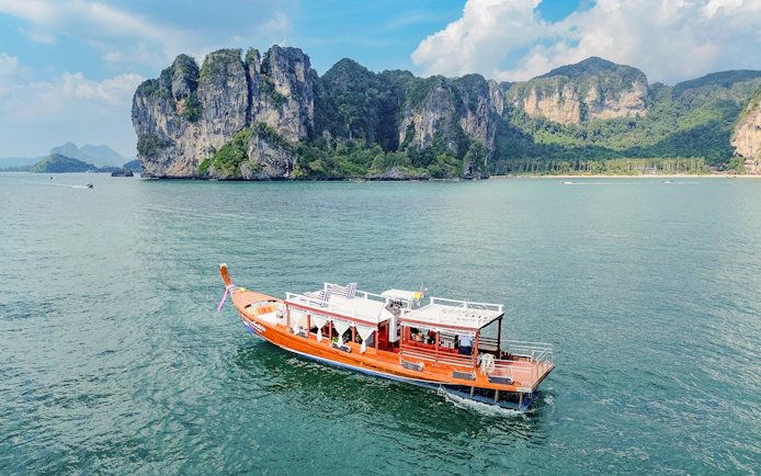 Long tail boat on the water near limestone cliffs, Ko Hong, Thailand.