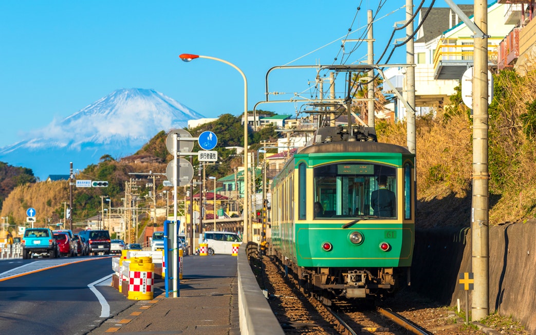 Enoshima Railway train traveling along the coast in Kamakura with Mount Fuji in the background.