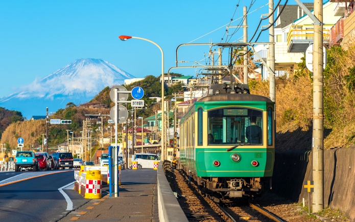Enoshima Railway train traveling along the coast in Kamakura with Mount Fuji in the background.