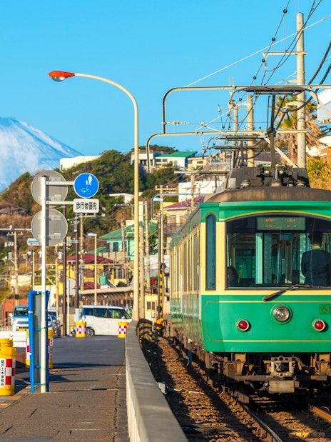 Enoshima Railway train traveling along the coast in Kamakura with Mount Fuji in the background.