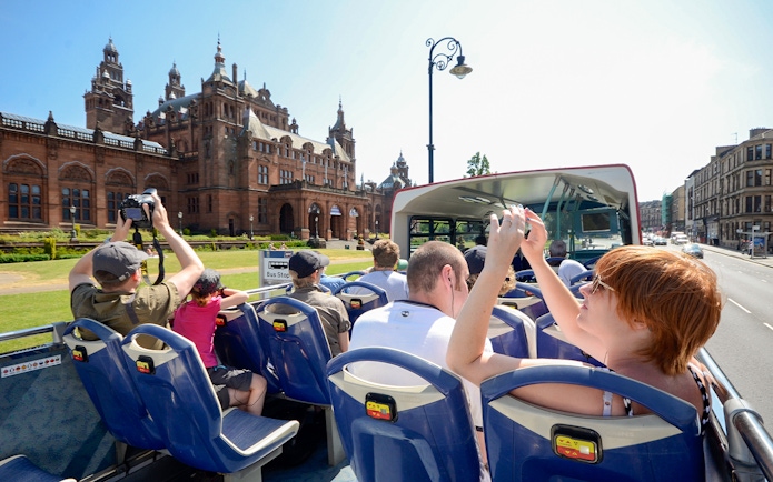 Open-top bus tour passing Kelvingrove Art Gallery in Glasgow.