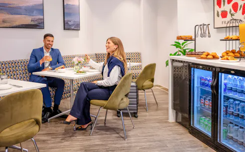 Guests enjoying refreshments at Plaza Premium Lounge, London, with snacks and drinks available.