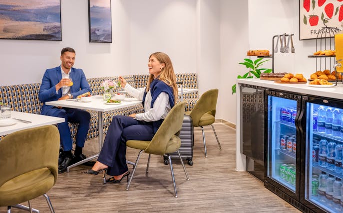 Guests enjoying refreshments at Plaza Premium Lounge, London, with snacks and drinks available.