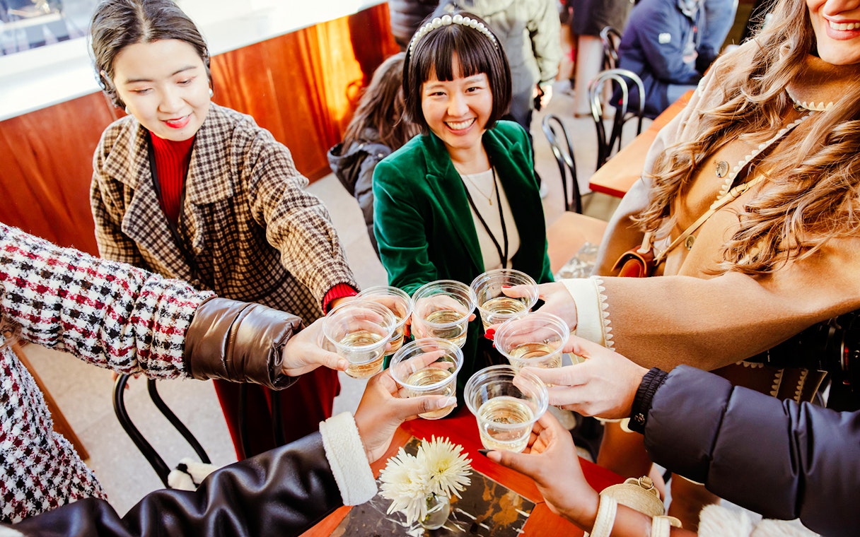 Group toasting with drinks at Rockefeller Center holiday event.
