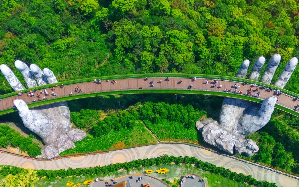 Golden Bridge held by giant hands in Ba Na Hills, Vietnam, surrounded by lush greenery.