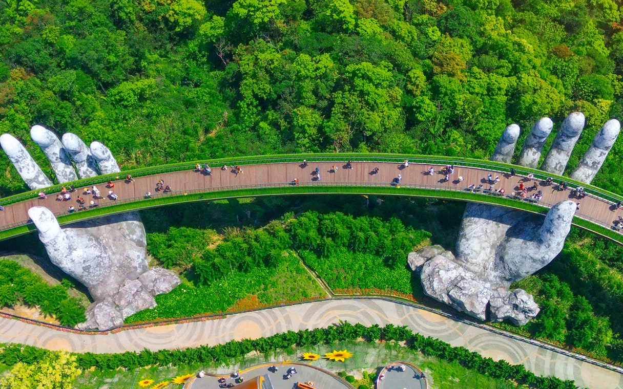 Golden Bridge held by giant hands in Ba Na Hills, Vietnam, surrounded by lush greenery.