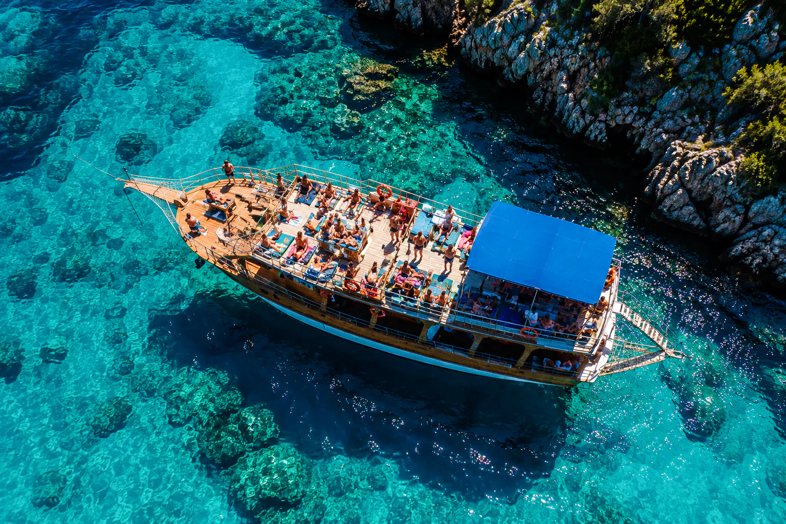 Cruise boat with tourists on clear turquoise waters near Alanya coast.