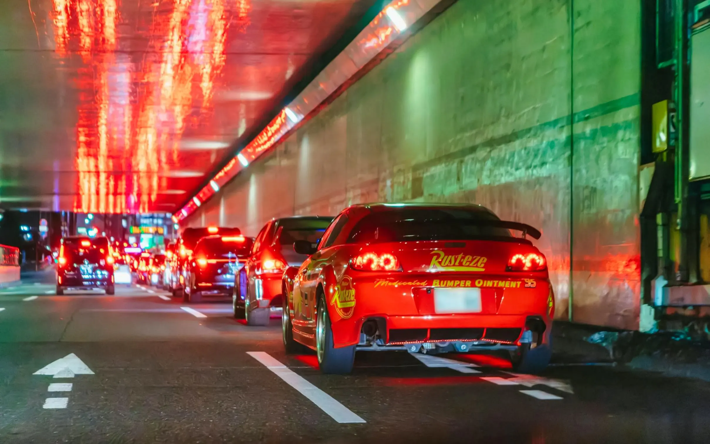 Cars driving through a neon-lit Tokyo tunnel for Fast & Furious Tokyo Drift III Experience.