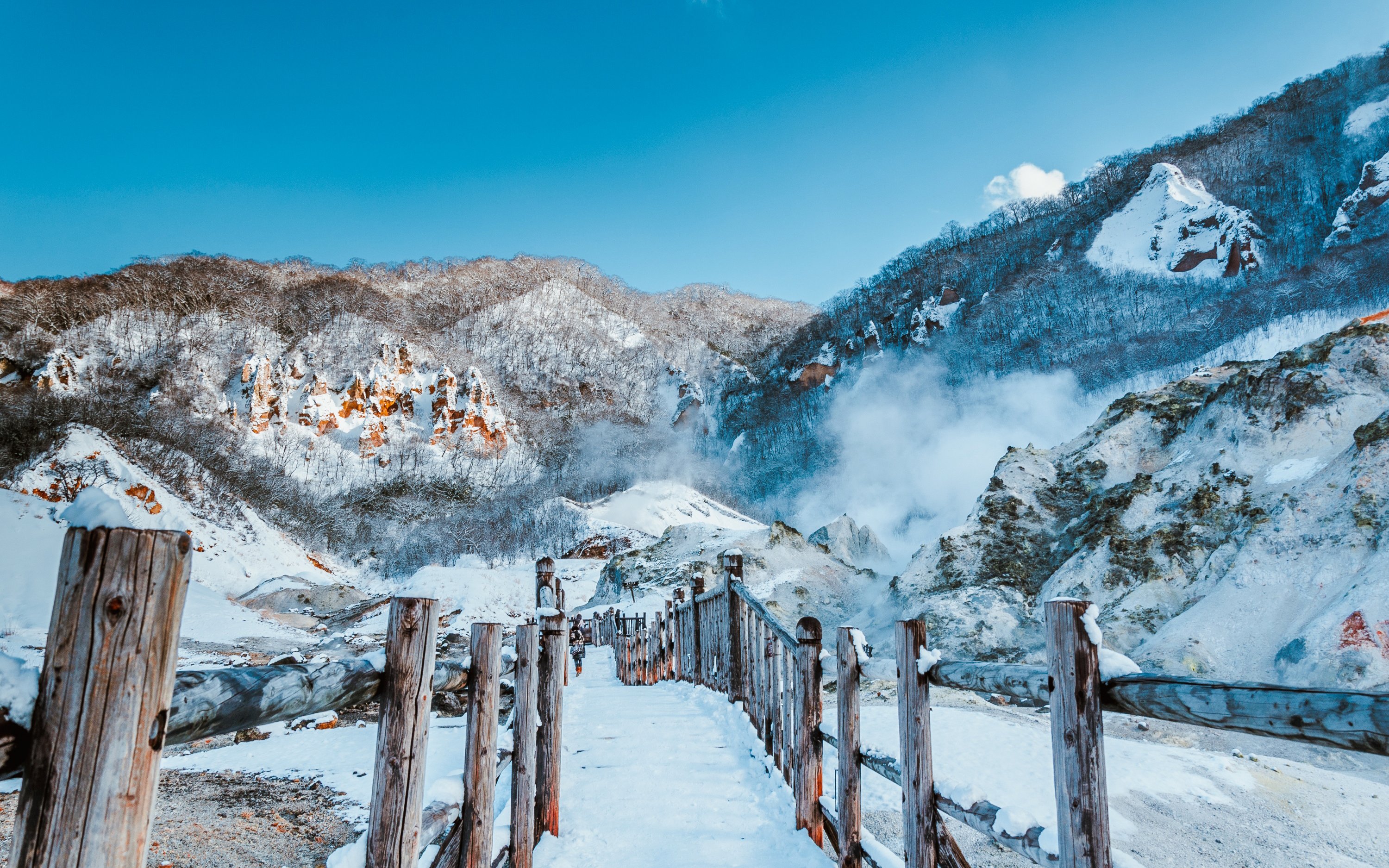 Wooden walkway through snowy Jigokudani Hell Valley, Noboribetsu, Hokkaido, Japan, with steaming vents.