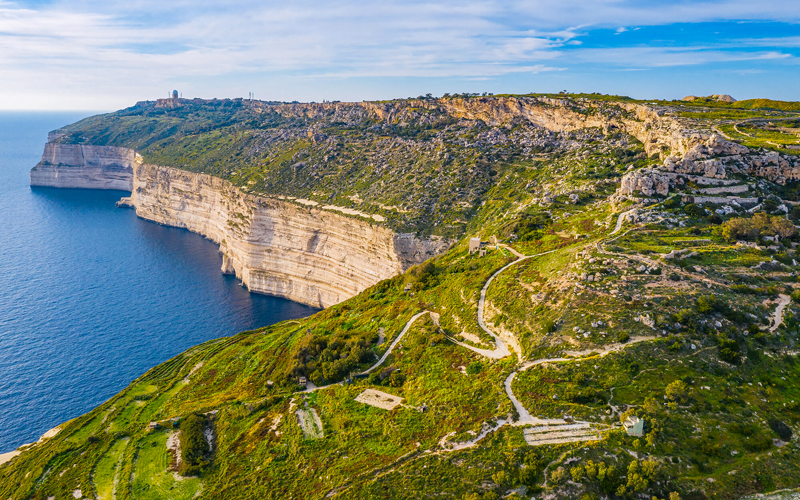 Dingli Cliffs overlooking the Mediterranean Sea, Malta, with winding paths and lush greenery.