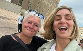 Two people smiling in front of a historic building in Stockholm during a city exploration game.