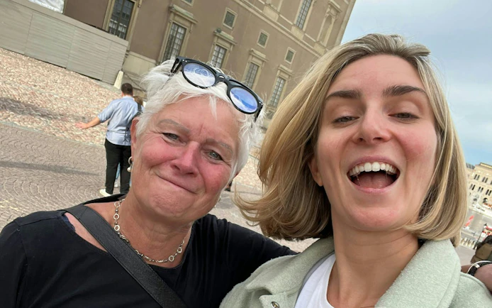 Two people smiling in front of a historic building in Stockholm during a city exploration game.