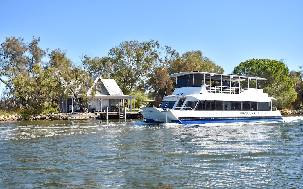 Cruise boat on Murray River passing a riverside house.
