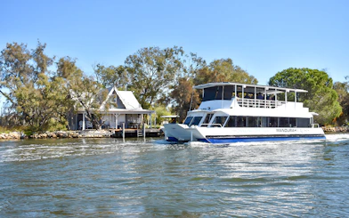 Cruise boat on Murray River passing a riverside house.