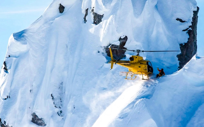 Helicopter landing on snowy glacier during Juneau tour with dog sledding.