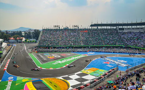 Cars racing on the track at Formula 1 Mexico Grand Prix with a packed stadium.