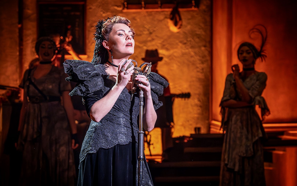Performer singing on stage during Hadestown musical.