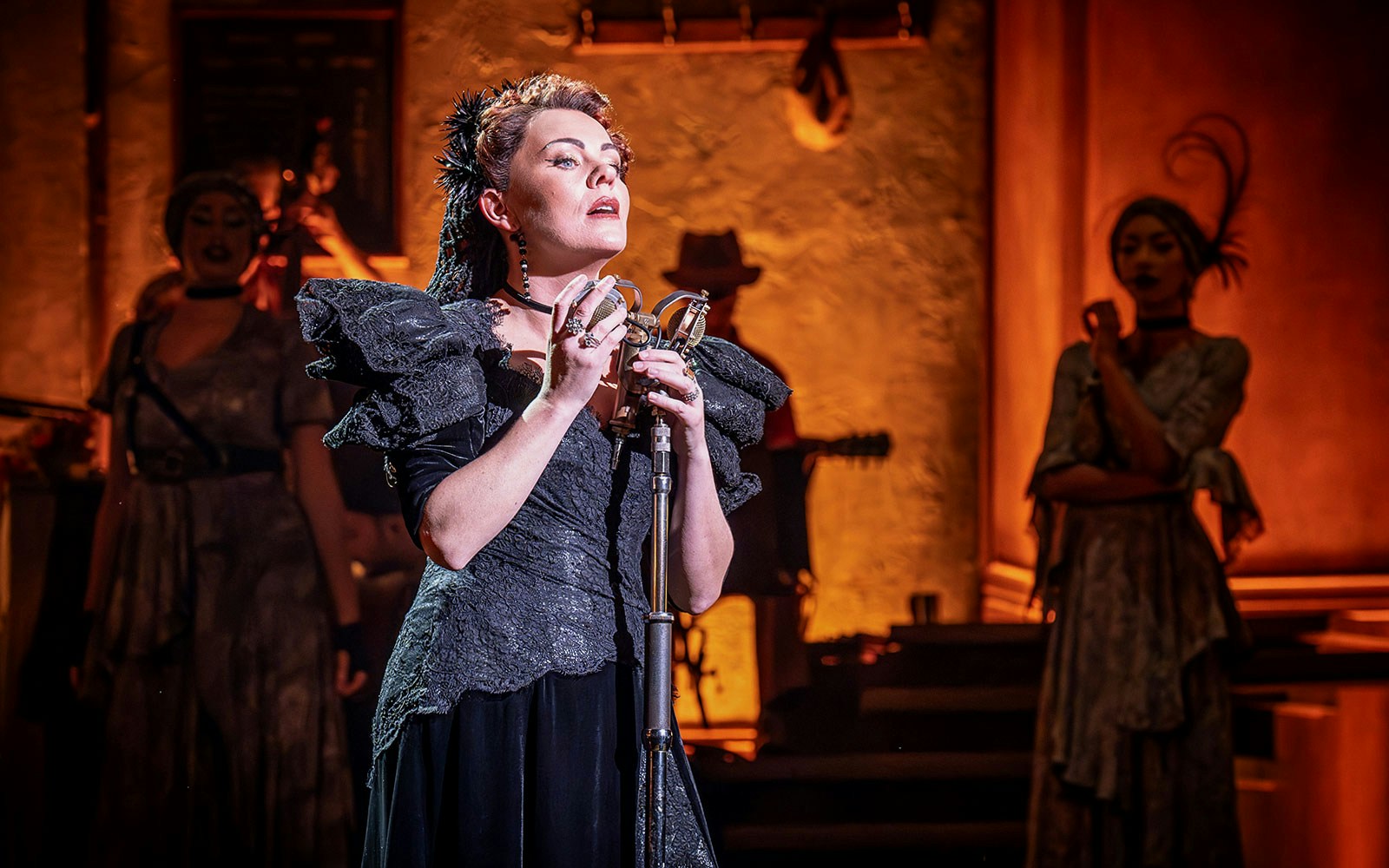 Performer singing on stage during Hadestown musical.